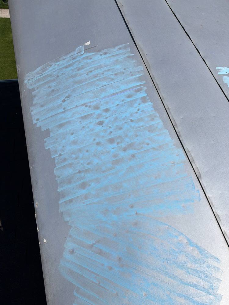 Hail dents on metal ridge cap highlighted with blue chalk, storm damage documentation Fauquier County