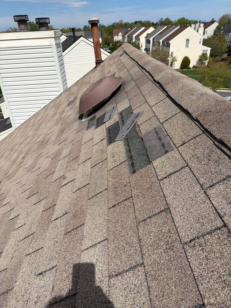 Wind damage with torn and missing shingles exposing mat near roof ridge, Prince William County Virginia